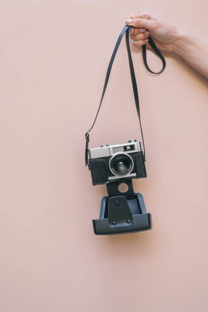 istock Hand holding a Vintage camera isolated at pink wall 968935366