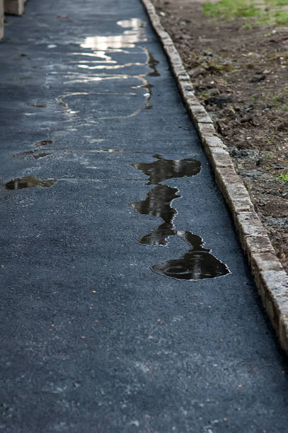 istock fresh asphalt covered with puddles of water reflecting the sky 968935972