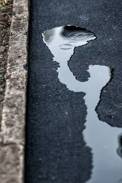 istock fresh asphalt covered with puddles of water reflecting the sky 968936056