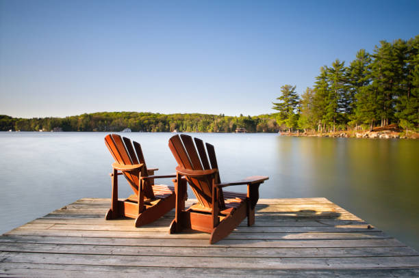 sedie muskoka su un molo di legno - adirondack chair foto e immagini stock