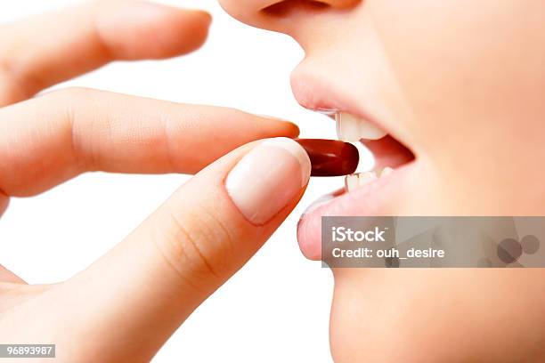 Young Lady With Red Pill Between Her Teeth Before Taking It Stock Photo - Download Image Now