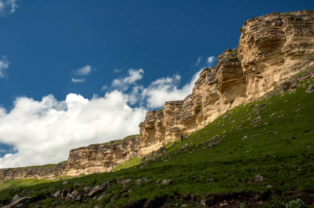 istock Yellow rocks with green grass, blue sky with white cloud 968942624