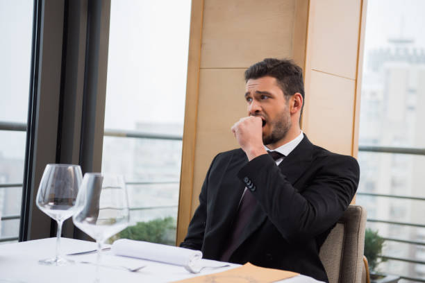 istock portrait of tired man yawing while sitting at table in restaurant 968948394