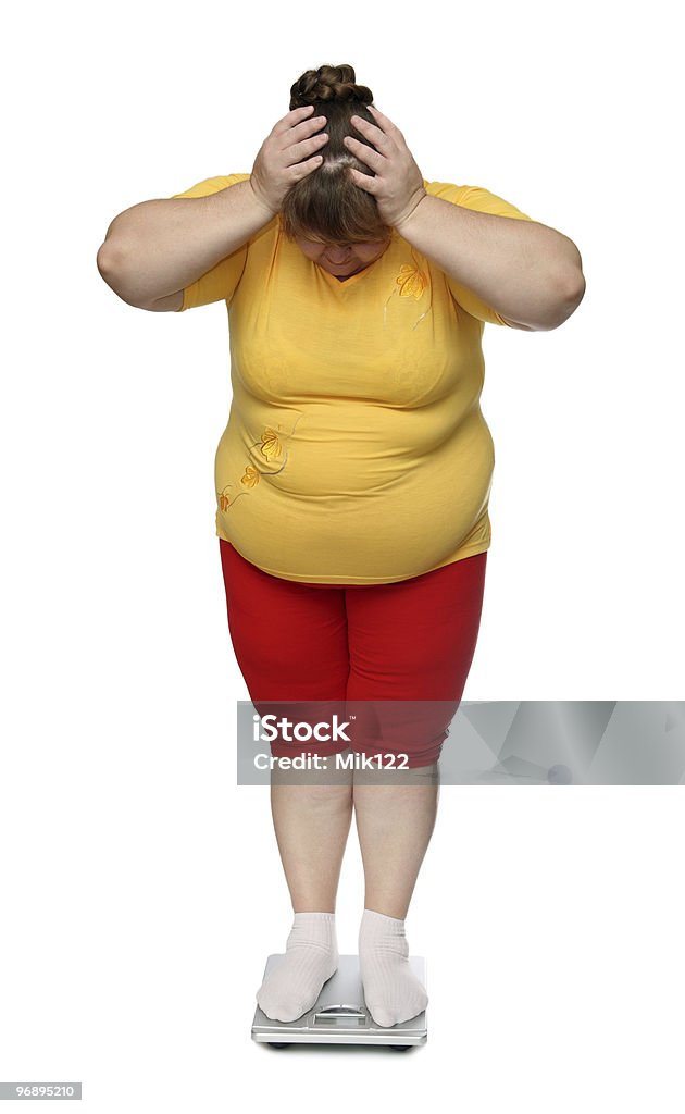 Overweight woman standing on a scale women with overweight standing on scales isolated on white Adult Stock Photo