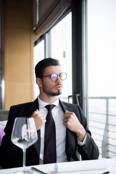 istock pensive man in suit and eyeglasses looking away while waiting for order in restaurant 968955736