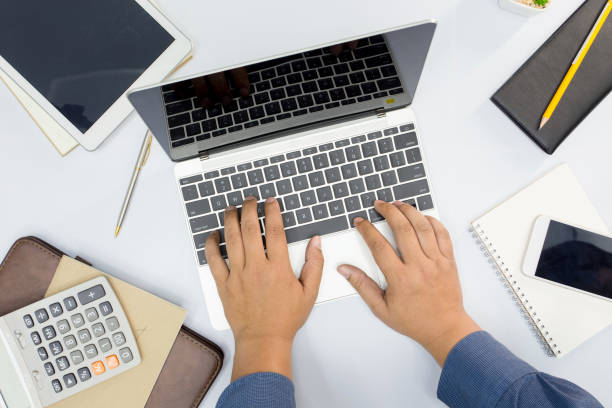 istock Businessman using computer laptop and other office supplies on white table in the office. Top view 968956862