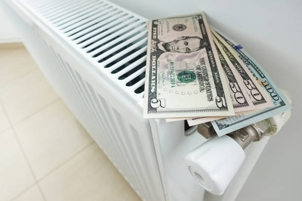 istock Reduce your energy bill for house heating with us dollars banknotes on white radiator 968959380