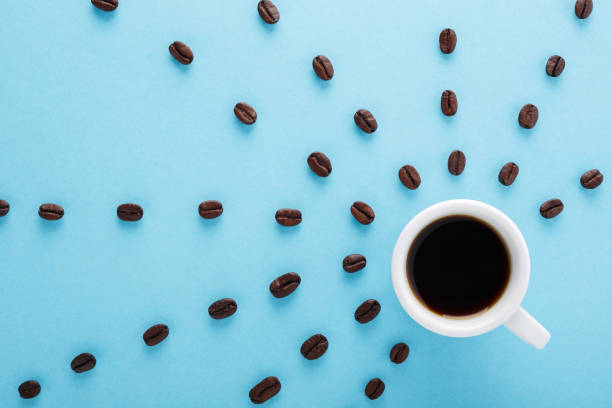 taza de negro café con granos de café sobre fondo azul pastel. - coffee black coffee cup coffee bean fotografías e imágenes de stock