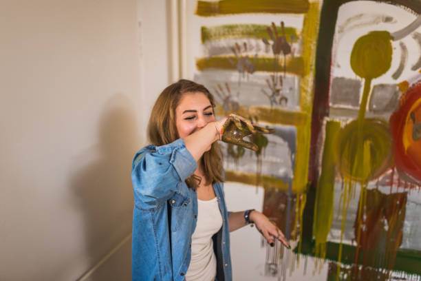 istock Young beautiful woman having fun while painting an image on the wall 968964722