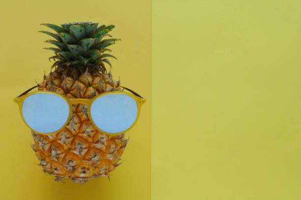 istock Pineapple fruit with yellow sunglasses on yellow color background. 968973114