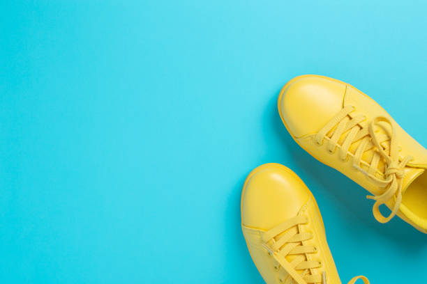 istock Pair of yellow shoes on blue background. 968976880