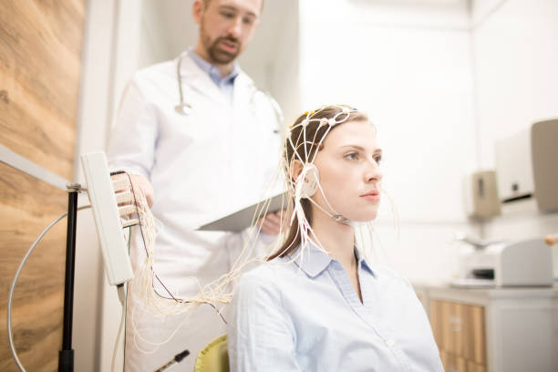 Eeg procedure Young patient with electrode on head and her doctor controlling the procedure electrode stock pictures, royalty-free photos & images