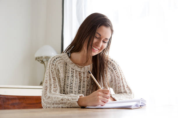 istock female student sitting at desk and writing in books 968990918