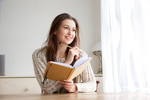 Portrait of smiling college student with book and pencil