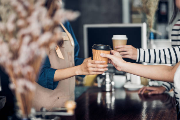 Barista served take away hot coffee cup to customer at counter bar in cafe restaurant,coffee shop business owner concept,Service mind waitress. Barista served take away hot coffee cup to customer at counter bar in cafe restaurant,coffee shop business owner concept,Service mind waitress barista stock pictures, royalty-free photos & images