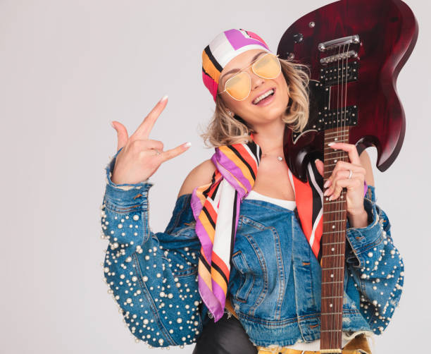 istock woman makes rock on sign while holding guitar on shoulder 968994560
