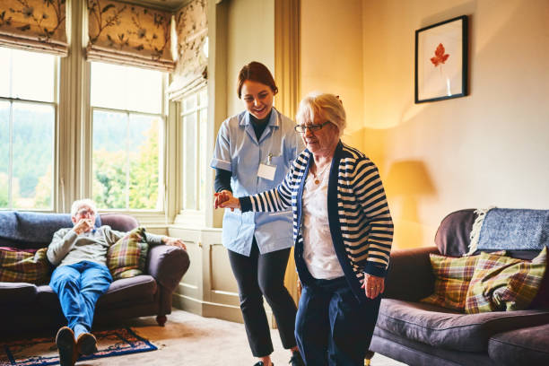 infirmière prise en charge de vieille femme de marcher à l’intérieur - healthcare worker home caregiver senior adult care photos et images de collection