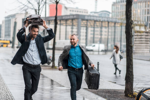 istock Businessman running in the rain holding a suitcase and a briefcase 969013764