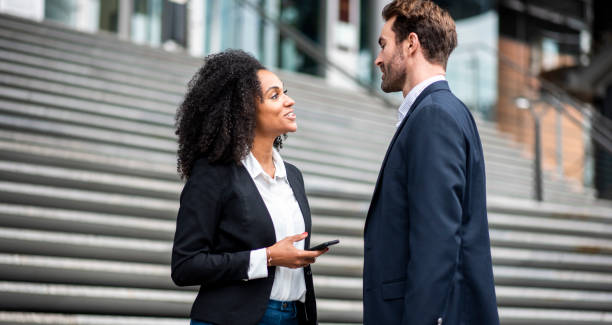 istock Two businesspeople talking outside the office and using smart phone 969013812