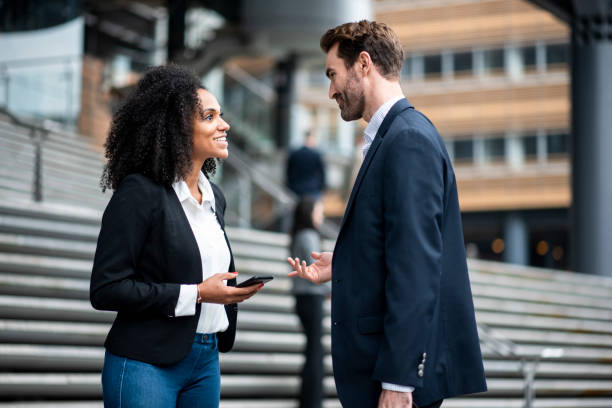 istock Two businesspeople talking outside the office and using smart phone 969013828