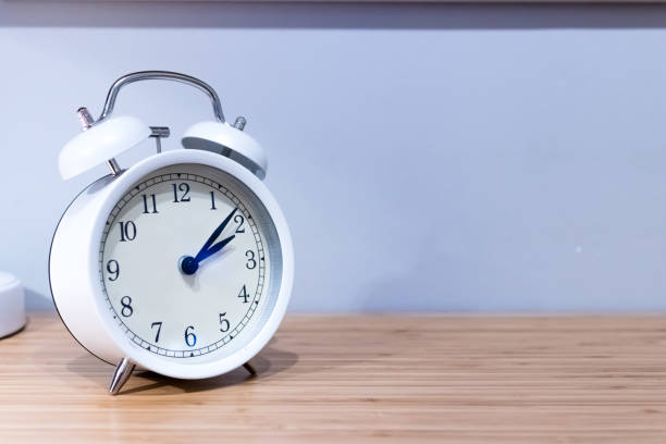 istock White alarm clock on wooden desk 969014556