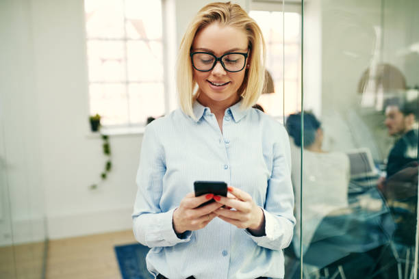 istock Smiling businesswoman standing in an office sending a text message 969027816