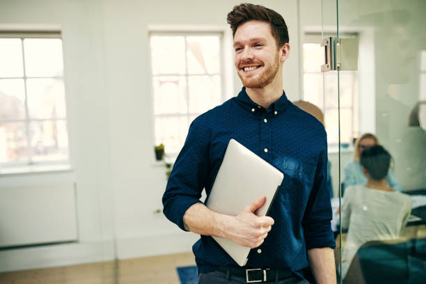 istock Smiling young businessman carrying a laptop in an office 969030254