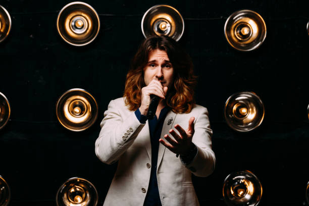 istock men singer with long hair, with microphone on the stage 969035092