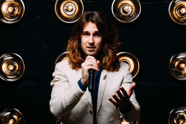 istock men singer with long hair, with microphone on the stage 969035102