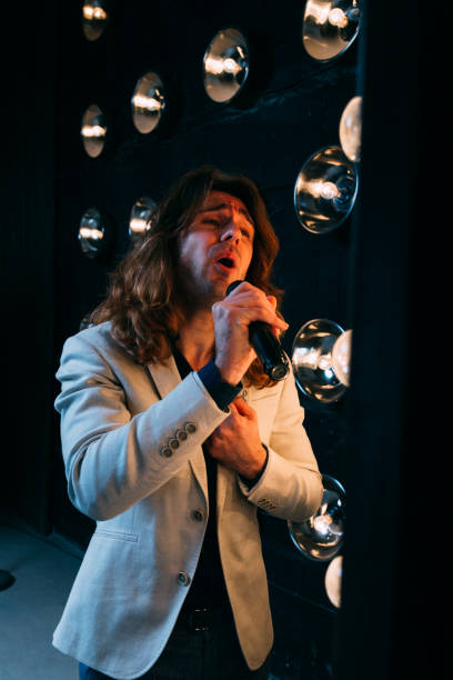 istock men singer with long hair, with microphone on the stage 969039516