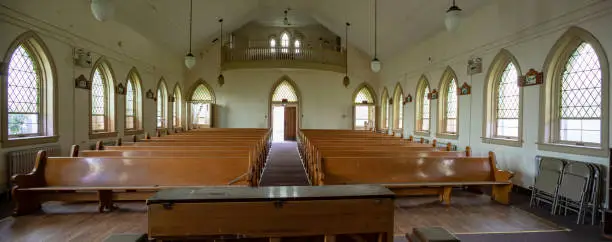 Interior of abandoned church with wooden pews inside prison yard.