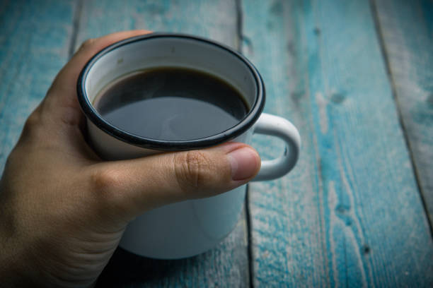 istock man holding in hand white iron mug 969053030