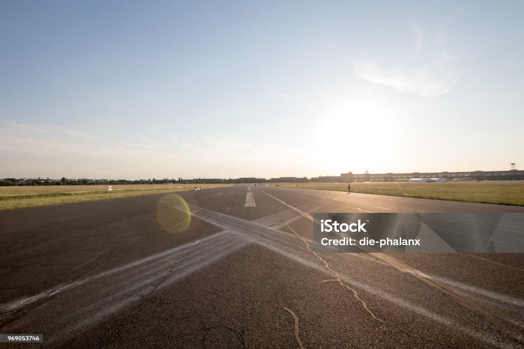 Road in perspective in the plain with horizontal signs to X. Road in perspective in the plain with horizontal signs to X. Asphalted road with white signs and sun at sunset in the background, effect of light in the lens. Long straight in perspective as airport Adventure Stock Photo