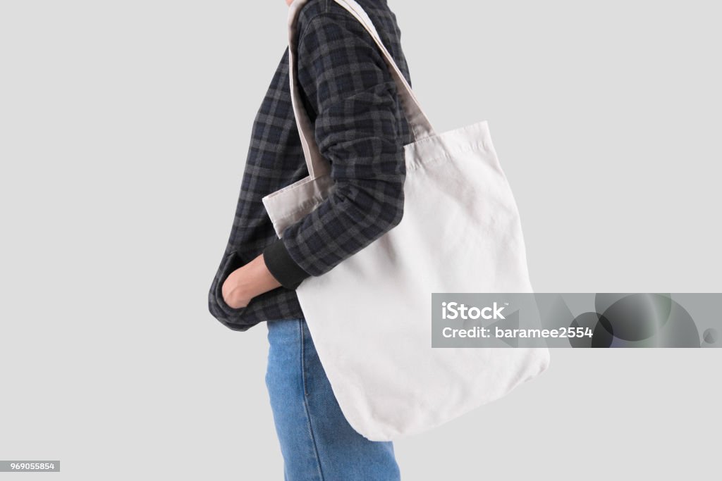 Girl is holding bag canvas fabric for mockup blank template isolated on gray background. Tote Bag Stock Photo