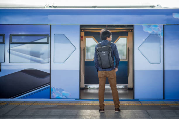 jeune homme asiatique, debout devant le métro train sur le quai de la gare dans la ville. concept de mode de vie urbain - door attendant photos et images de collection