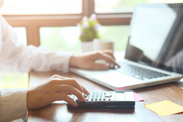 istock Man calculate finance business using calculator and computer laptop analysis data at morning time in modern office. 969066480