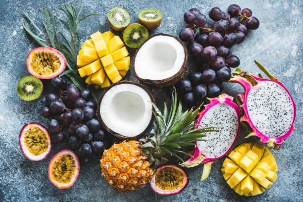 Assortment of exotic tropical fruits, top view Assortment of exotic tropical fruits, top view. Passionfruit, dragonfruit, mango, pineapple, kiwi, grapes and coconut. Fresh food background. Healthy eating, vegan and summer concept tropical fruit stock pictures, royalty-free photos & images