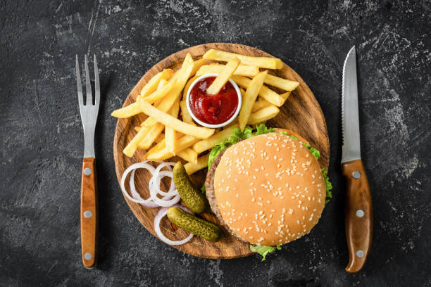 Beef burger, french fries, pickles, onion and ketchup Beef burger, french fries, pickles, onion and ketchup. Table top view. Concept of fast food big plate of food stock pictures, royalty-free photos & images