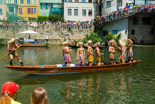 Tübingen, Germany - May 31, 2018: People having fun on boats, on the Neckar River. The boat is called 'Stocherkahn' (poke boat). The teams are mostly students. Some of the people and some boats are in disguise . At the end is a fun race called 'Stocherkahn competition'. Many spectator are along the track.
