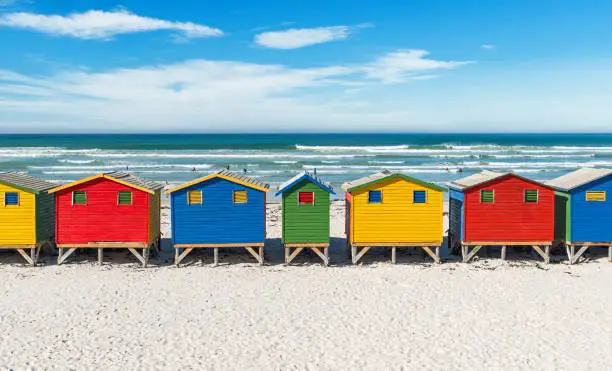 Symmetric landscape of Muizenberg beach with its famous colorful beach huts and surfers paradise near Cape Town, South Africa.