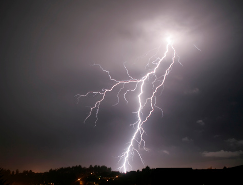 In a wild thunderstorm with high winds and pounding rain, lighting bolts strike repeatedly over cactus and junipers during a night time summer storm in southeast Colorado’s Comanche National Grasslands.