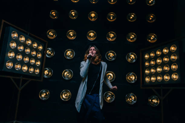 istock men singer with long hair, with microphone on the stage 969089078