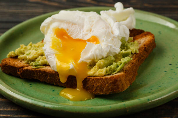 istock Toast and poached egg with avocado on a green plate on wooden table 969093352