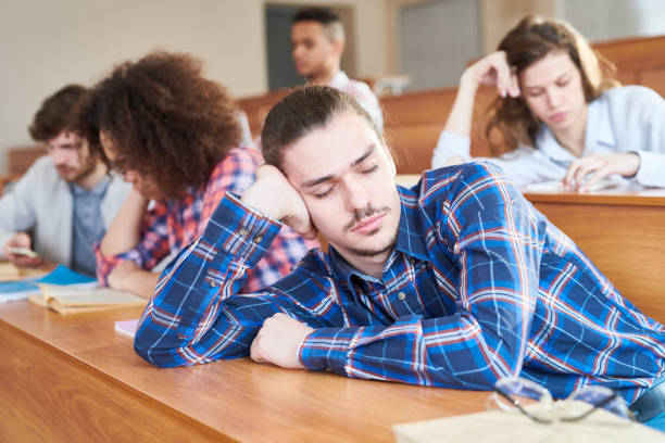 Sleep at lesson Young man sitting at desk and sleeping during a lesson at college male college student sleeping through lecture stock pictures, royalty-free photos & images