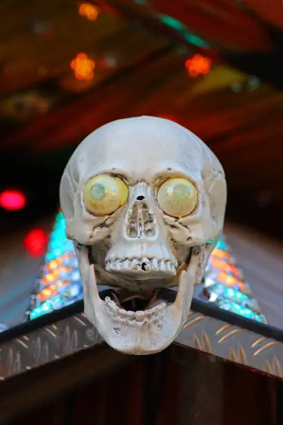 laughing skull with eyes at the entrance of a ghost train, multi colored light in the back