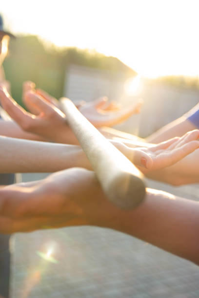 istock Blurred hands hold a blurred, wooden stick. teambuilding activity with a stick and hands. colleagues. rays of the sun fall, light up your hands and stick, show the way 969100566