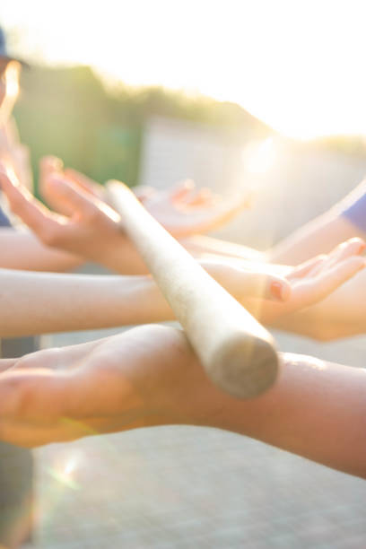 istock Blurred hands hold a blurred, wooden stick. teambuilding activity with a stick and hands. colleagues. rays of the sun fall, light up your hands and stick, show the way 969100576