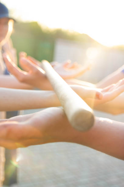 istock Blurred hands hold a blurred, wooden stick. teambuilding activity with a stick and hands. colleagues. rays of the sun fall, light up your hands and stick, show the way 969100594