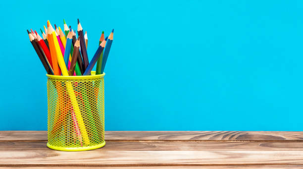 istock Holder with colored pencils on wooden table on blue background. Space for text. 969108048