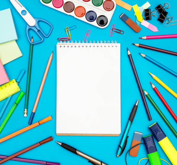 istock Notepad with school supplies on blue. Top view. Space for text. 969108194